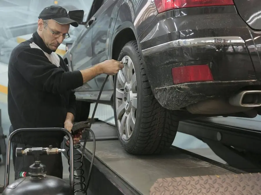 Mechaniker prüft Reifendruck an einem Fahrzeug auf der Hebebühne